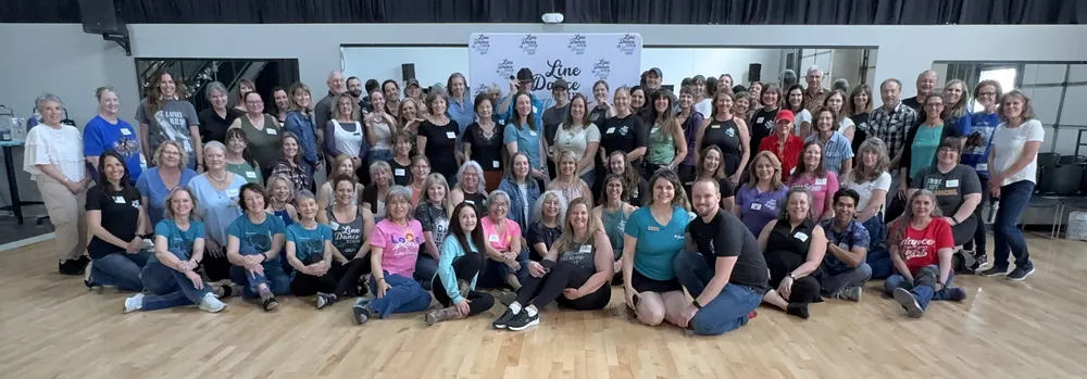 A large group of line dancers gathered together for a group photo