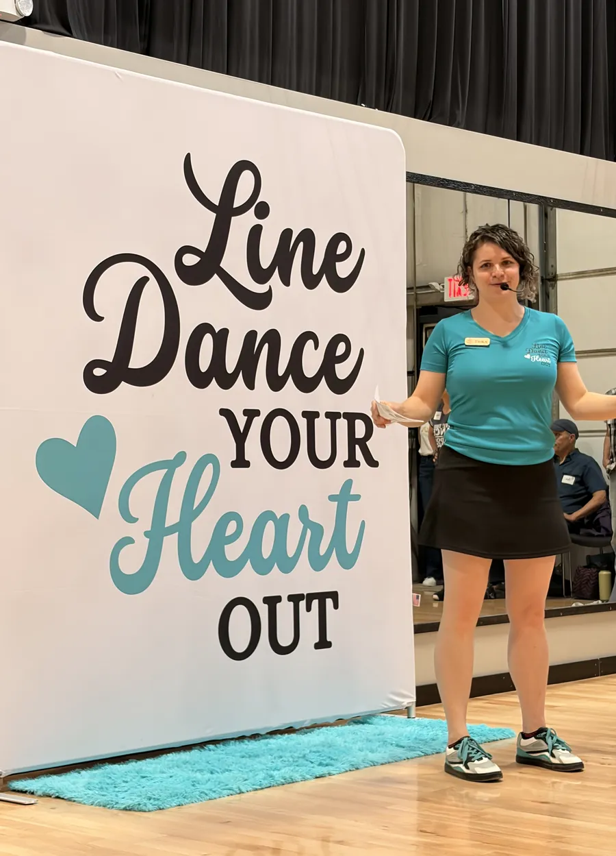 Erika standing beside a Line Dance Your Heart Out banner