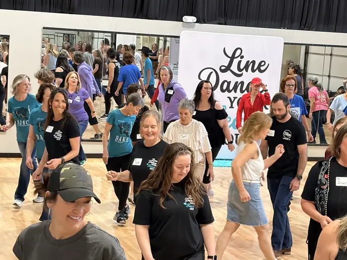 Dancers smiling and moving together in a packed studio