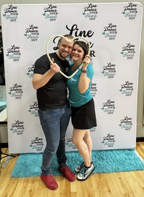 Two dancers posing with a heart-shaped prop at the event photo booth